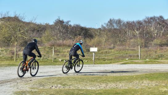 Mountainbikers fietsen over een duinpad