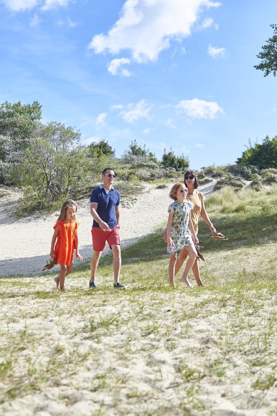 Een gezin wandelt in de duinen op een zomerse dag