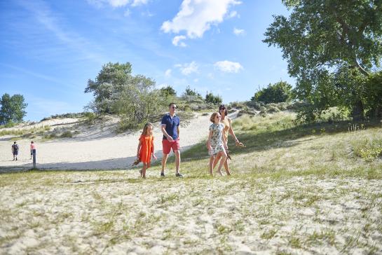 Een gezin wandelt in de duinen op een zomerse dag